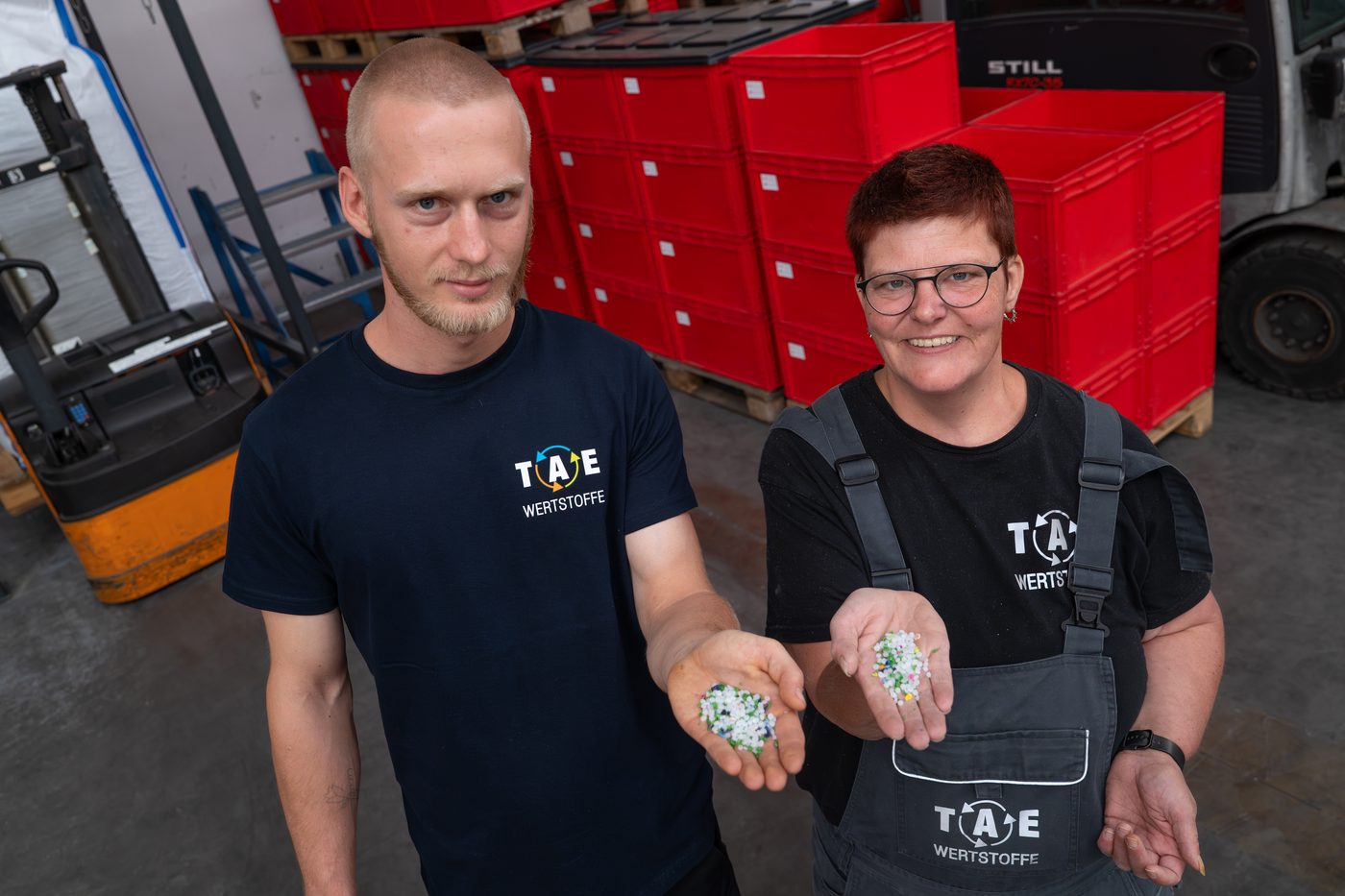 Mitarbeiter von TAE Wertstoffe zeigen aufbereitetes Kunststoff-Mahlgut